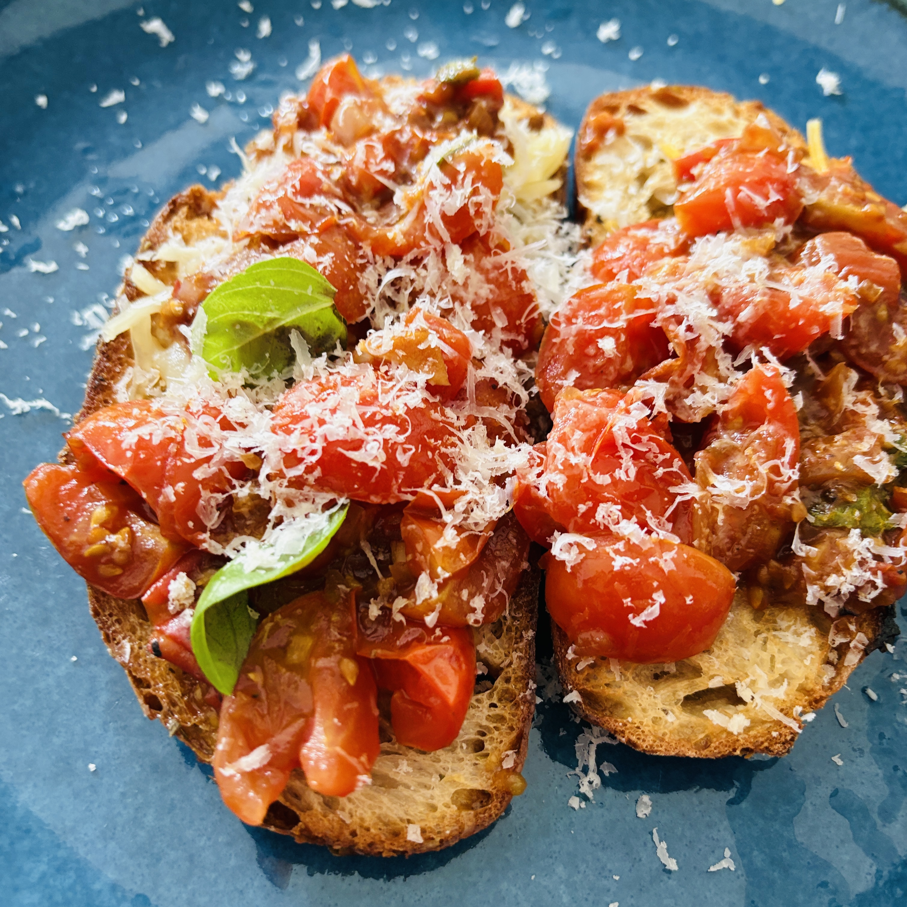 Geröstetes Brot mit Tomaten, Burrata, Basilikum und Parmesan – einfaches Rezept für einen herzhaften Snack.